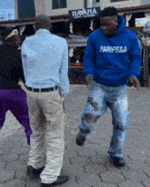 a man in a blue paripesa sweatshirt dancing