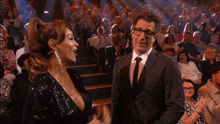 a man in a suit and tie talks to a woman in a sequined top