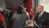 a man in a suit and tie talks to a woman in a crowd