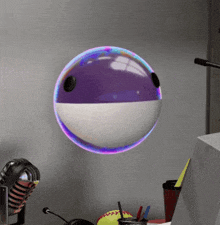 a purple and white ball is floating in the air on a desk with a microphone .