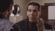 a man in a suit and tie is looking at another man in a room .