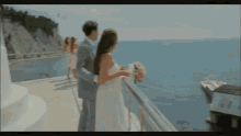 a bride and groom standing on a balcony overlooking the ocean .