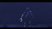 a person in a hooded jacket is standing in a dark room with a sword in their hand .
