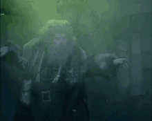 a man with a beard is standing in a dark room with green smoke coming out of the ceiling .