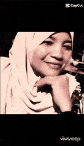 a woman wearing a hijab and a watch is smiling .