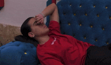 a woman laying on a blue couch wearing a red shirt that says givova