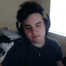 a young man wearing headphones and a necklace is looking at the camera .