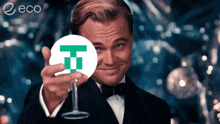 a man in a tuxedo holds up a wine glass with a t on it