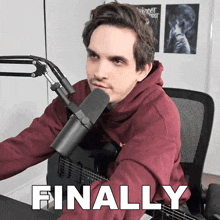 a man sitting in front of a microphone with the word finally written below him