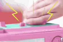 a person is pressing a button on a pink toy with lightning bolts coming out of it ..