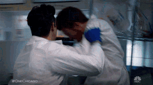 a man in a lab coat is fighting another man in a lab coat in a scene from one chicago .