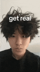 a young man with messy hair is making a funny face with the words `` get real '' on his face .