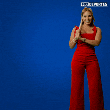a woman in a red jumpsuit is holding a baseball bat in front of a blue background with fox deportes written on it