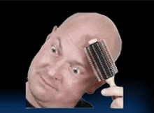 a bald man is holding a hair brush to his head