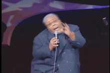 a man in a suit is singing into a microphone while making a funny face .