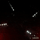 a group of people are dancing in a dark room with a circular pattern on the ceiling .