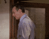 a man in a purple shirt and tie is standing in front of a glass door with the word brian on it