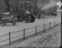 a black and white photo of a fence and a cannon that says pathe at the bottom