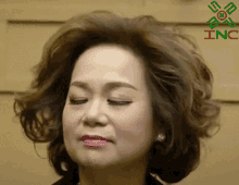 a woman with her eyes closed is standing in front of a sign that says inc.