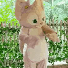 a stuffed animal dressed as a fox is standing in front of a fence .