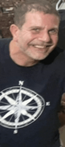 a man with a compass on his shirt is smiling .