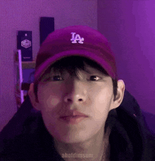 a young man wearing a purple la hat