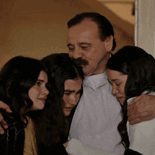 a man with a mustache is surrounded by three women