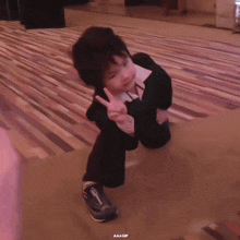 a little boy in a suit giving a peace sign with a aa + gif watermark