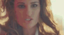 a close up of a woman 's face with long hair and a blurred background .