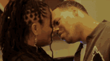 a man and a woman are touching their foreheads and the man is wearing a shirt with the letter e on it