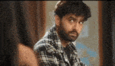 a man with a beard is looking at himself in the mirror and making a funny face .