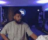 a man with a beard is sitting in front of a neon sign that says ' neol '