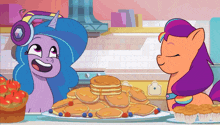 two ponies are standing next to a plate of pancakes and cupcakes