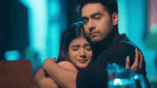 a man and a woman are hugging each other .