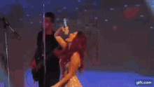 a woman is singing into a microphone while a man plays a guitar on stage .