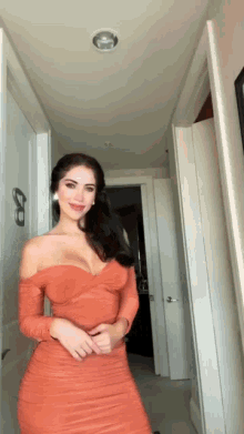 a woman in an orange dress is standing in a hallway and smiling