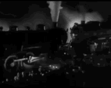 a black and white photo of a crowd of people watching a train go by