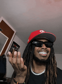 a man with dreadlocks wearing sunglasses and a hat with a letter s on it