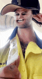 a man wearing a hat and a yellow jacket has a tattoo on his chest