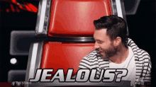 a man in a striped shirt is sitting in a chair with the words jealous written on it