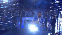 a man in a blue shirt holds a trophy in front of a crowd that says ' live ' on the bottom