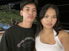 a man and a woman are posing for a picture and the man is wearing a black shirt that says " growing "
