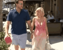 a man and a woman are walking down the sidewalk holding hands