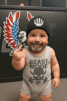 a baby wearing a tank top that says beast mode giving the middle finger