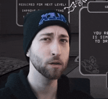 a man with a beard wearing a beanie that says x-hm on it