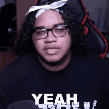 a man with curly hair wearing glasses and a bandana that says yeah