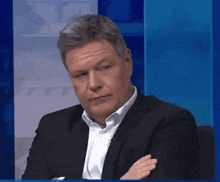 a man in a suit is sitting in front of a blue screen