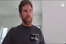 a man with a beard is wearing a t-shirt that says `` no '' on it .