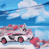 a man is sitting on top of a white and pink car