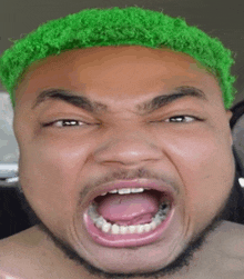 a man with green hair is making a funny face with his mouth wide open .